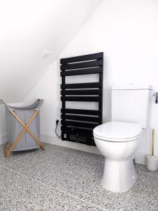 La salle de bains est pourvue de toilettes blanches et d'une étagère noire. dans l'établissement Appartement cosy chic La Ville au Monnier, à Pleurtuit