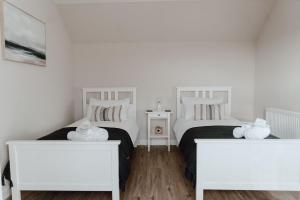two beds in a white room with two white tables at Cleod9 -Croft house at 9 Garenin in Carloway