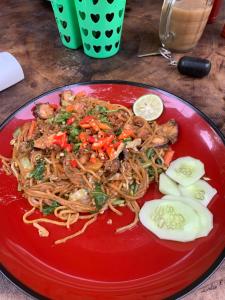 a red plate of food with noodles and vegetables at Tiu Ronton River , Bungalows Camping and Trekking in Pawenang