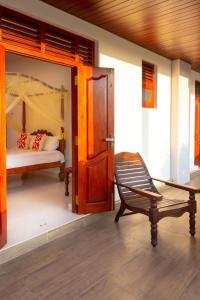 Holiday Home Kalutara في كالوتارا: غرفة بسرير وكرسي بجانب باب