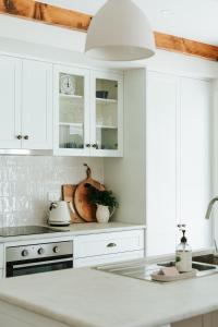 a white kitchen with white cabinets and a sink at Kookaburra Cottage - 10 minutes from Mount Gambier CBD in Yahl