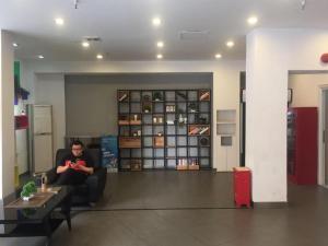 a man sitting in a chair in a room at 7Days Inn Shenzhen Longgang Nanlian Metro Station Branch in Shenzhen