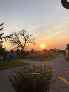 a sunset over a road with a tree and a house at Wohnwagen am Ostsee-Küstenradweg in Zweedorf