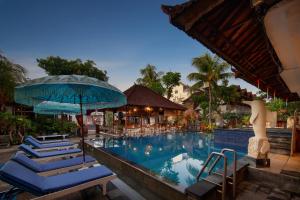 a pool at a resort with blue chairs and an umbrella at Legian Village Hotel - CHSE Certified in Legian