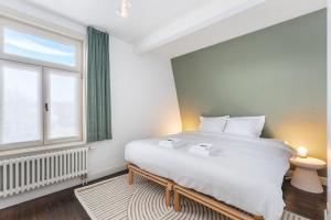 a bedroom with a large white bed and a window at Magique 31 - Luxeverblijf met tuin & parking in Oostduinkerke