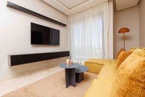 a living room with a couch and a tv and a table at Stylish 1BR flat in Hay Riad Central Rabat in Rabat