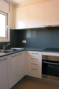 una cocina con armarios blancos y fregadero en Residencial Super Stop Apartaments Torre Valentina, en Sant Antoni de Calonge