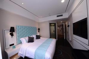 a bedroom with a large bed with a blue headboard at Xana Lite Hotel Beijing Daxing International Airport in Yufa