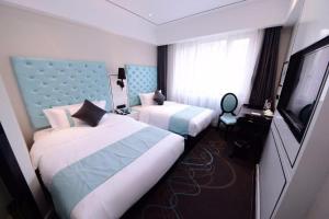 a hotel room with two beds and a flat screen tv at Xana Lite Hotel Beijing Daxing International Airport in Yufa