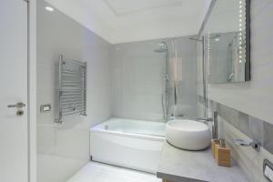 een witte badkamer met een wit bad en een wastafel bij Pangea Luxury Rooms Oplonti in Torre Annunziata