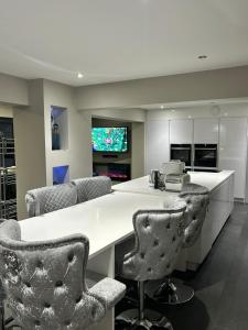 a kitchen with a white counter and some chairs at Big Modern Home in Murrayfield next to the Murrayfield Stadium in Edinburgh