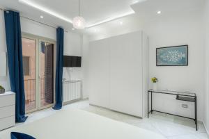 een slaapkamer met witte muren en blauwe gordijnen bij Pangea Luxury Rooms Oplonti in Torre Annunziata