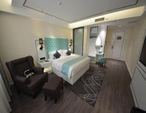 a hotel room with a bed and a chair and a bed and a couch at Xana Lite Korla Shihua Avenue Longquehe in Korla