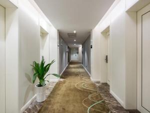 a corridor of an office with a plant on the floor at Xana Hotelle Changsha Social Work College Branch in Yangtianhu