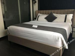 duże łóżko z białą pościelą i czarnymi poduszkami w obiekcie Xana Hotelle Xiamen Airport Zone Government w mieście Heshan
