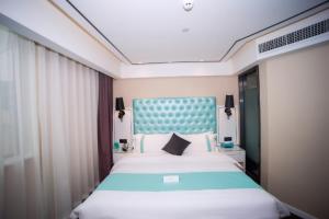 Schlafzimmer mit einem großen Bett mit blauem Kopfteil in der Unterkunft Xana Lite Nanchong Pengan Wuxing Garden Branch in Peng'an