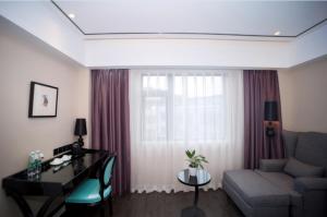 ein Wohnzimmer mit einem Sofa, einem Schreibtisch und einem Fenster in der Unterkunft Xana Lite Nanchong Pengan Wuxing Garden Branch in Peng'an