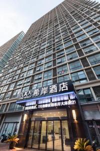 ein hohes Gebäude mit einem Schild davor in der Unterkunft Xana Hotelle Nanchang Gaoxin Xincheng Wuyue Plaza in Nanchang