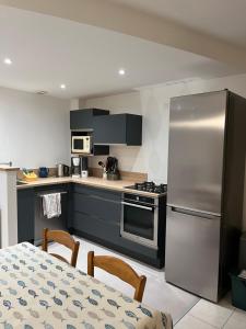 a kitchen with a stainless steel refrigerator and a table at Le Moulin de la Butte in Huisnes-sur-Mer