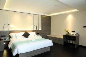 ein Schlafzimmer mit einem großen weißen Bett und einer Bank in der Unterkunft Xana Lite Jiangmen Yingbin West in Jiangmen