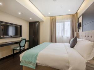 a bedroom with a bed and a desk and a television at Xana Hotelle Suqian Soho Ginza Branch in Suqian
