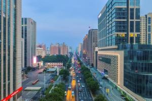una calle con tráfico en una ciudad con edificios altos en Xana Lite Shenyang Beiling Park Liaoning Building Branch en Shenyang