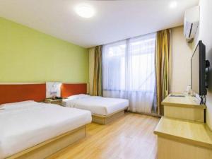 a hotel room with two beds and a television at 7 Days Inn Tianjin Binhai Passenger Station Huabei Ceramics in Binhai