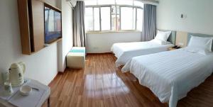 a hotel room with two beds and a television at 7Days Inn Changsha University in Xingsha