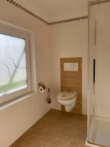ein Bad mit einem WC und einem Fenster in der Unterkunft Pension Seehund in Norden