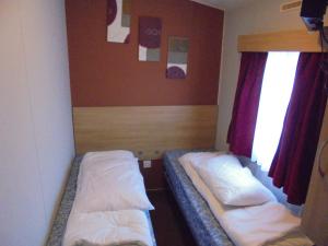 two beds in a small room with a window at 8 Berth Northshore (Warmth) in Winthorpe