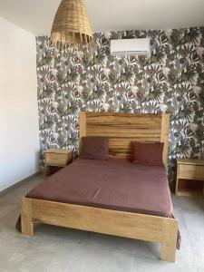 Cama de madera en un dormitorio con pared en villa de standing, en Sali Nianiaral