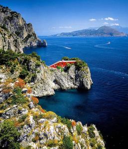 una casa roja en un acantilado en el agua en Boat & Breakfast Sorrento sailing, en Castellammare di Stabia