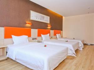 7 Days Premium Jinan Gaoxin Qu Wanda Plaza في Licheng: سريرين في غرفة باللون البرتقالي والأبيض