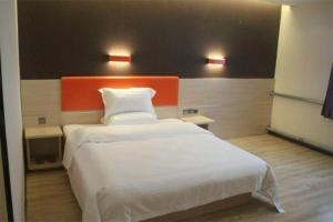 7 Days Premium Jinan Gaoxin Qu Wanda Plaza في Licheng: غرفة نوم مع سرير أبيض كبير مع اللوح الأمامي من البرتقال