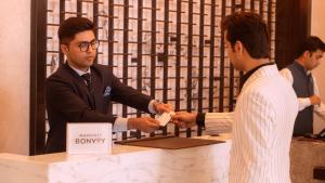 a man handing another man a transaction at a counter at Courtyard by Marriott Vadodara in Vadodara