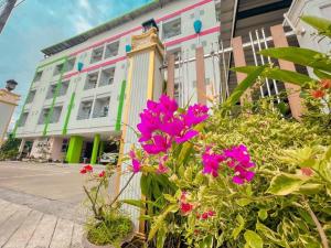 ein Gebäude mit rosa Blumen davor in der Unterkunft The Linux Garden Hotel (City Amphur Muang Yala) in Yala