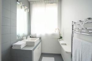 La salle de bains blanche est pourvue d'un lavabo et d'un miroir. dans l'établissement Rooftop Flat w/ outdoor terrasse, à Courbevoie