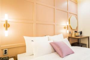 a bedroom with a white bed with a pink pillow at Plain Hotel in Chuncheon