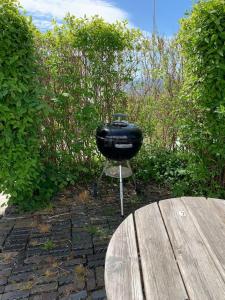 a barbecue grill sitting next to a wooden table at Cottage by the ocean in Ängelholm