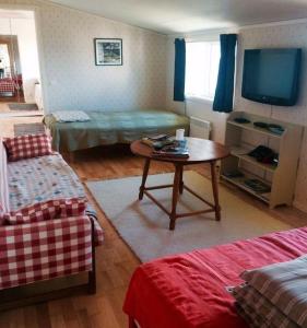 a living room with a table and a tv at Cottage by the ocean in Ängelholm