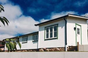a white house with green windows and a cloudy sky at Cottage by the ocean in Ängelholm