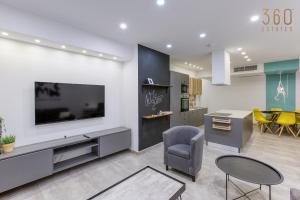 un soggiorno con TV, sedia e tavolo di Designer 3BR home with Private Balcony in Gzira by 360 Estates a Il-Gżira