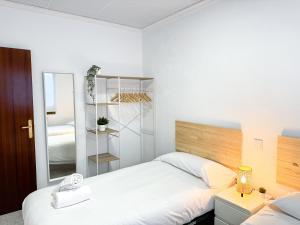 a white bedroom with a bed and a mirror at La Paloma del Pilar ComoTuCasa in Zaragoza