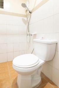 a white toilet in a white tiled bathroom at OYO 128 d'Builders Rooms Phase 2 in Manila