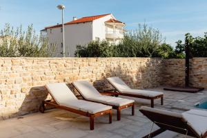eine Gruppe von Liegestühlen neben einer Ziegelmauer in der Unterkunft Olive Tree Apartments 2 in Vodice