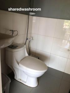 a bathroom with a white toilet and a sink at MIOKI HOMETEL in Batuan