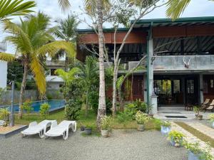 a building with a group of white chairs and palm trees at Hikka Lotus Garden in Hikkaduwa