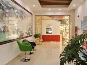 a lobby with a green chair in a building at GreenTree Inn Zhangye Ganzhou Train Station Orthopaedic Hospital in Zhangye