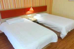 2 camas en una habitación de hotel con sábanas blancas en Home Inn-Qingdao Chongqing Zhong Road Licang Walking Street, en Laoshan
