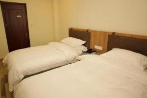 dos camas sentadas una al lado de la otra en un dormitorio en Yun Brand-Dalian Laodong Park Wuchang Street Ripple Hotel, en Dalian